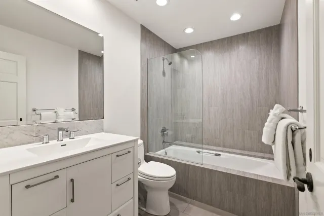 a bathroom with a toilet a sink a mirror a bathtub and shower