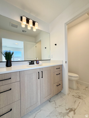 915 West Gold Ridge Ln Street St. George, UT 84790 - Photo 12 of 30 Spacious vanity featuring light wood-finish cabinetry with matte black hardware, a pristine white countertop, and an integrated rectangular sink