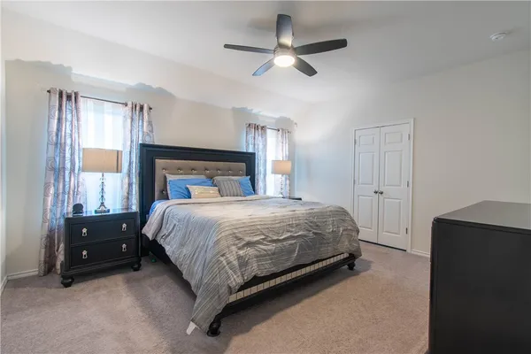 a bedroom with a large bed and a chandelier fan