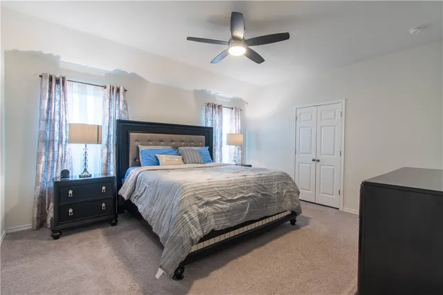 a bedroom with a large bed and a chandelier fan
