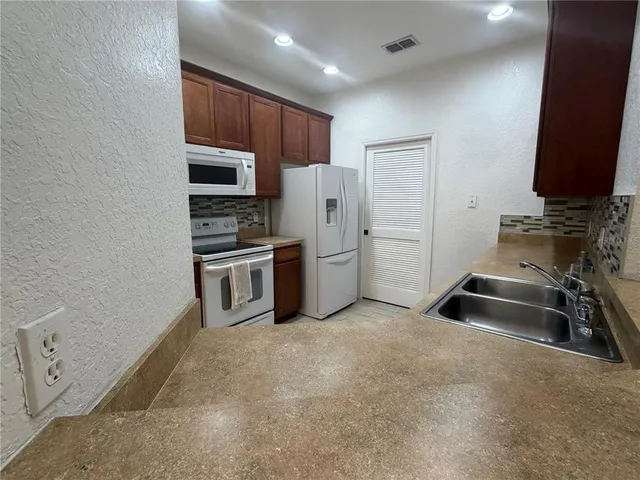 a kitchen with stainless steel appliances a refrigerator and a stove top oven