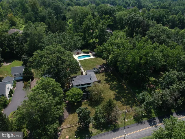 an aerial view of a house with yard outdoor and trees all around