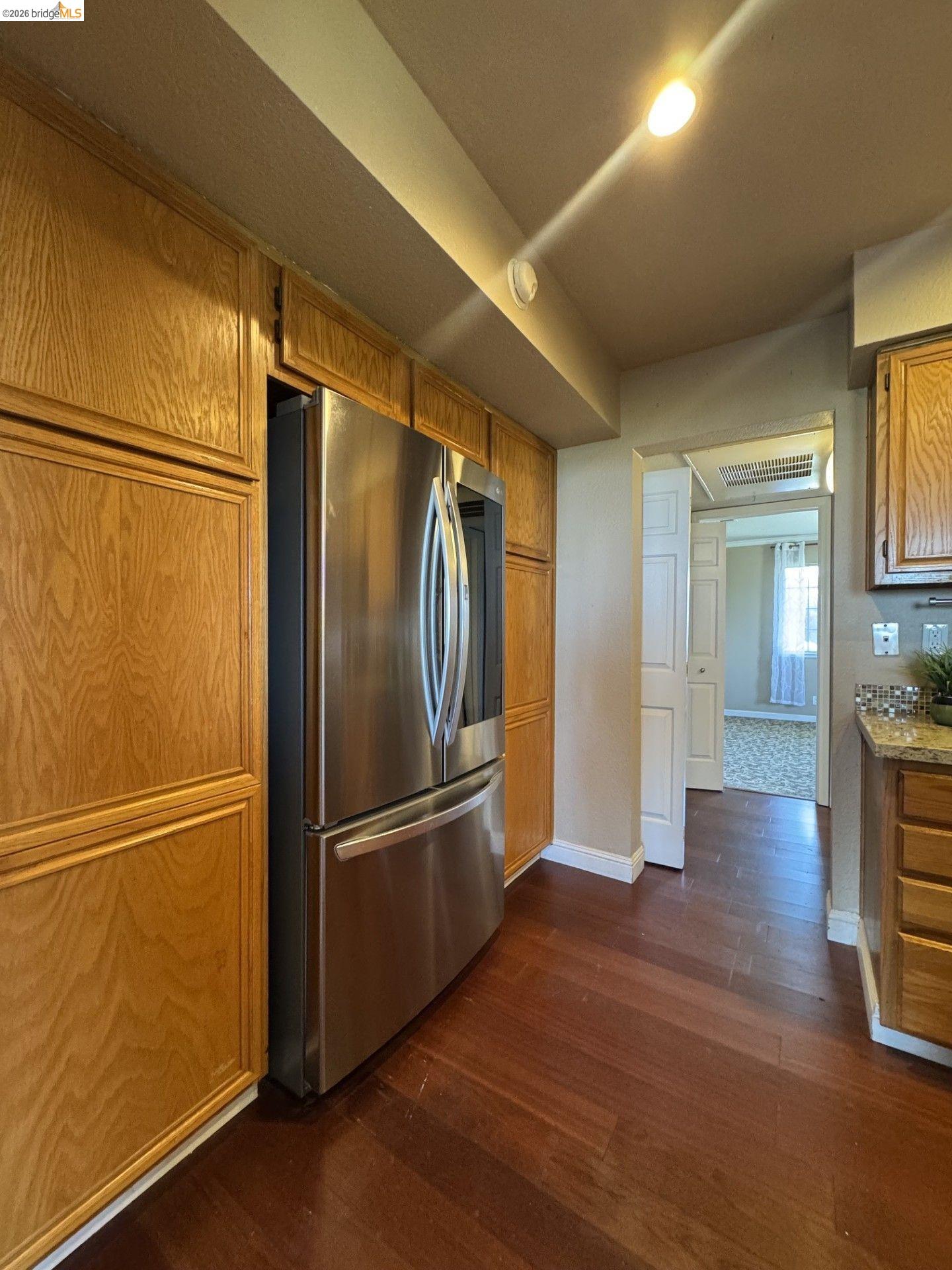 3623 Wells Road Oakley, CA 94561 - Photo 21 of 75 Stainless steel refrigerator, wood-finish flooring, recessed ceiling light, and built-in wood cabinetry