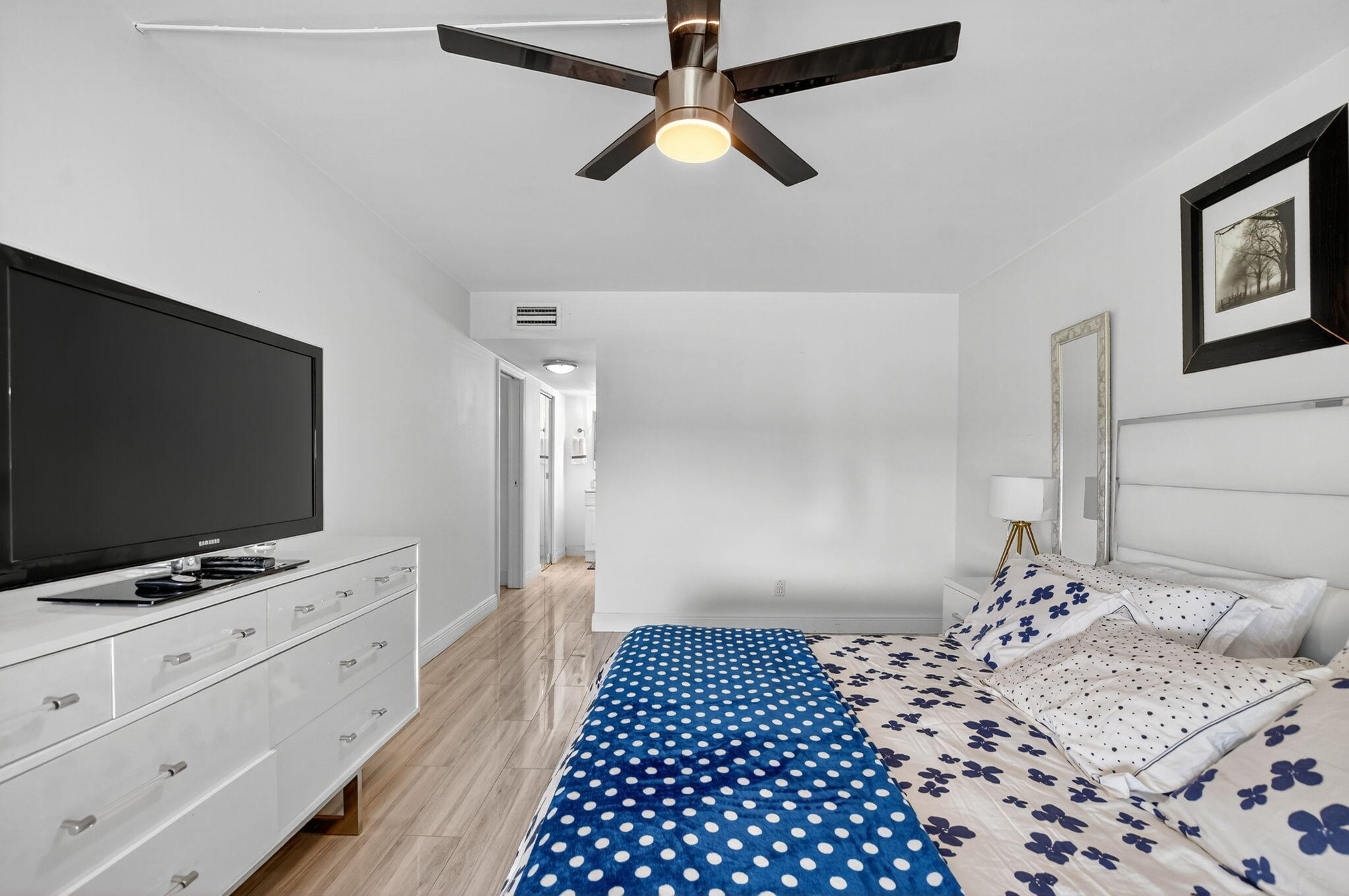 23277 Barwood Lane North, Unit 403 Boca Raton, FL 33428 - Photo 18 of 30 a view of a bedroom with wooden floor cabinet and a flat screen tv