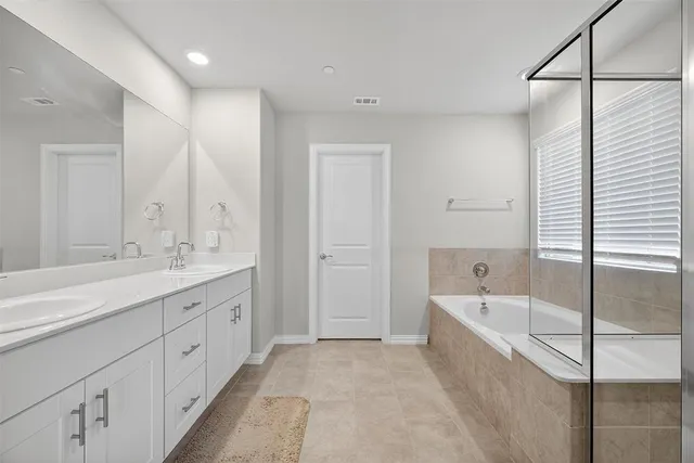 a spacious bathroom with a tub sink and mirror