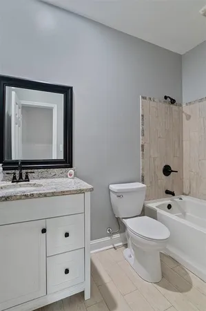 a bathroom with a granite countertop toilet a sink and a mirror