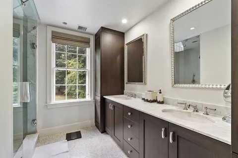 a bathroom with a double vanity sink mirror and shower