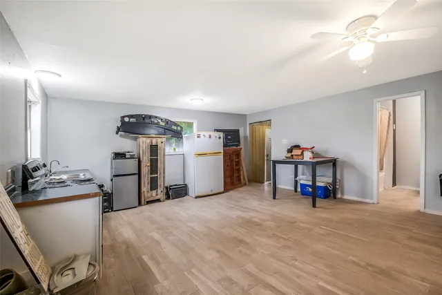 a view of a storage & utility room with closet fridge and wooden floor