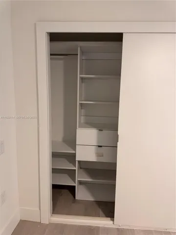 an empty room with wooden floor and a ceiling fan