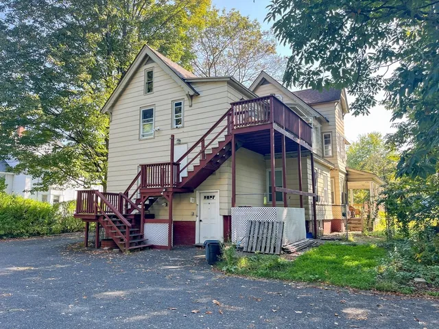 a view of a house with a small yard and a large tree