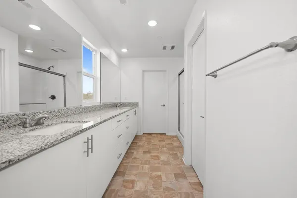 a bathroom with a granite countertop sink a large mirror and a shower