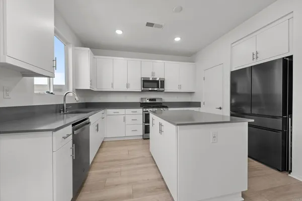 a kitchen with a sink a stove a refrigerator and cabinets