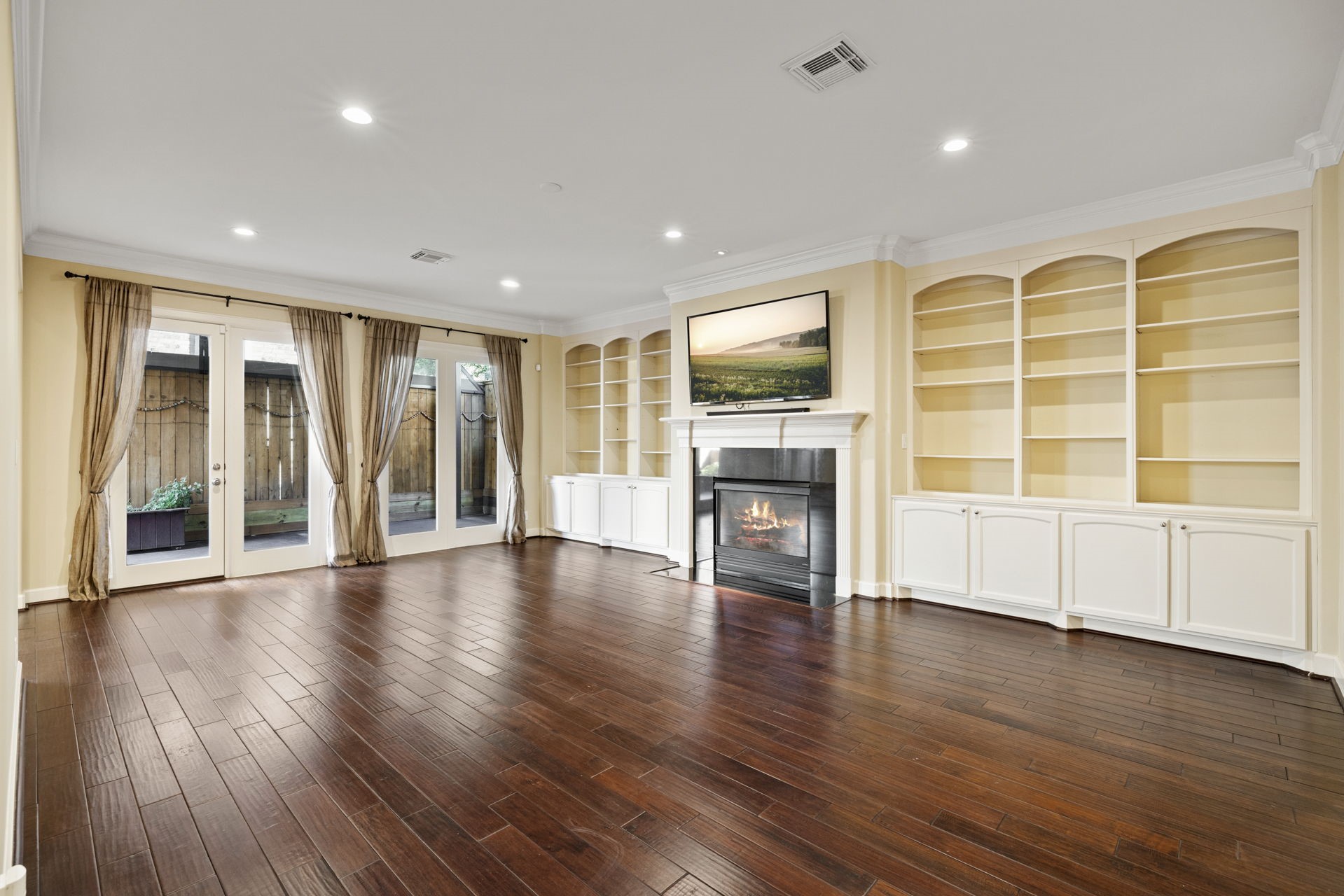 6310 Hermann Lake Drive Houston, TX 77021 - Photo 5 of 39 Side view of the living room with gorgeous built-ins, fireplace, hardwood floors and French doors that open to a large covered patio.