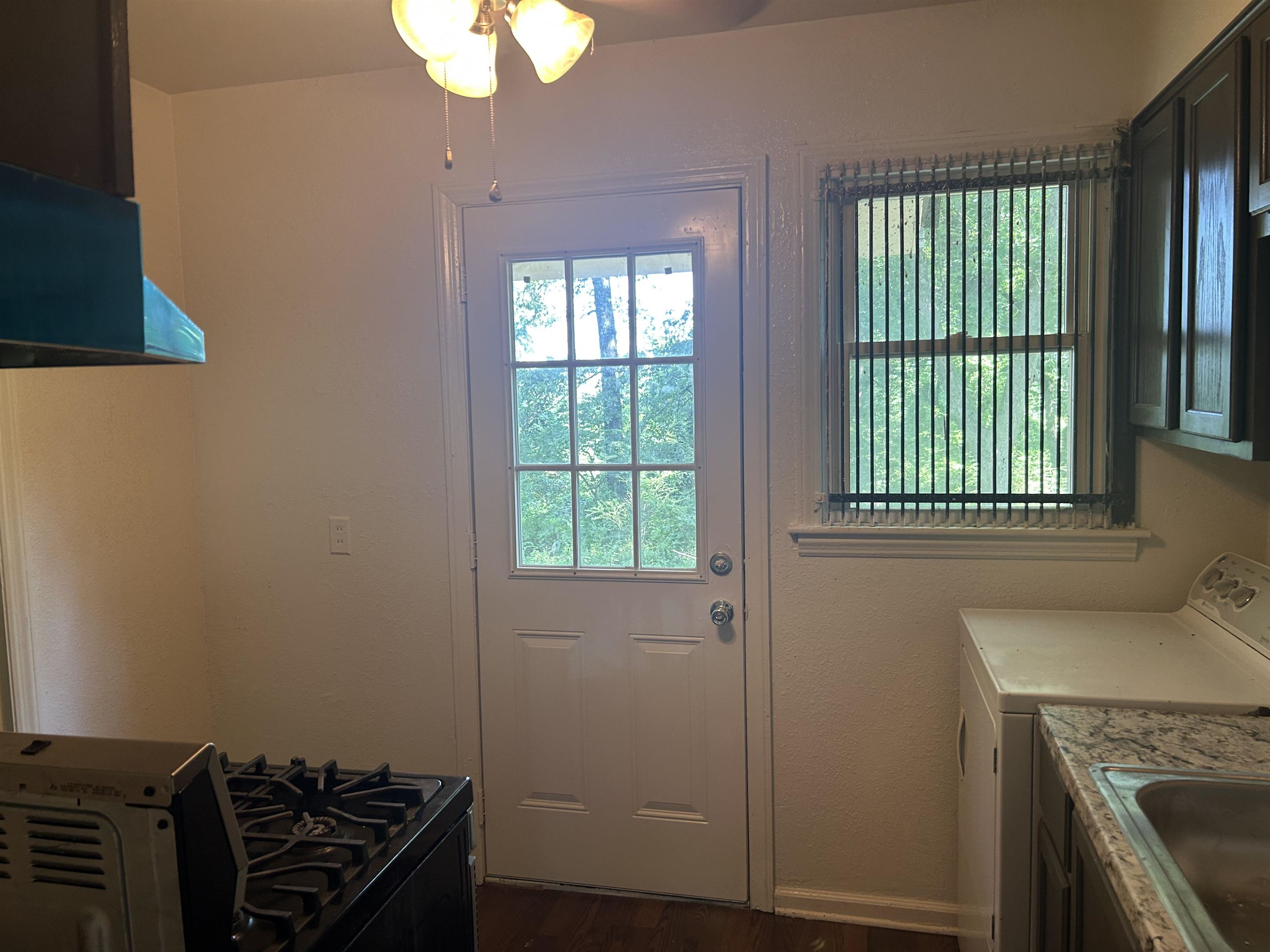 904 North Ball Road Memphis, TN 38106 - Photo 5 of 12 Kitchen space featuring a paneled door with glass inserts, a window with vertical blinds, dark wood-finish cabinetry, and a countertop with a polished surface