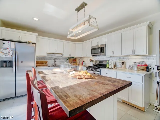 a kitchen with stainless steel appliances granite countertop a stove top oven a refrigerator a sink dishwasher a dining table and chairs with wooden floor