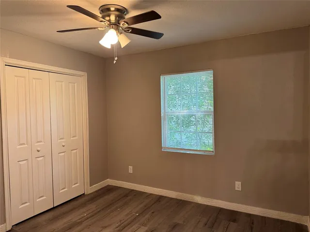 a view of an empty room with a window and wooden floor