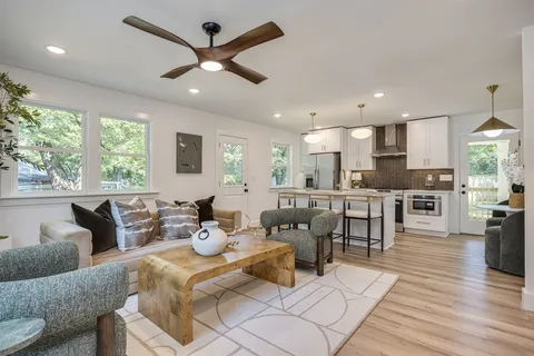a living room with furniture kitchen view and a large window