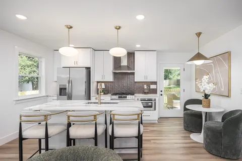 a kitchen with a dining table chairs stainless steel appliances and cabinets