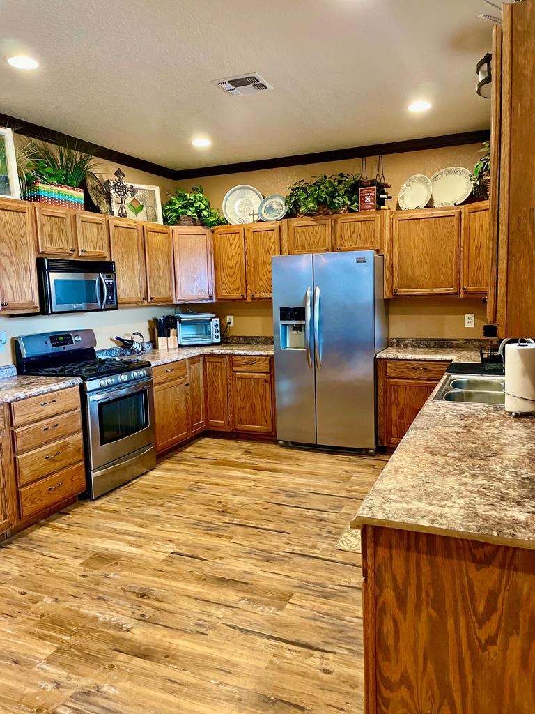 646 Victor Eckhardt Road Fredericksburg, TX 78624 - Photo 15 of 40 a kitchen with stainless steel appliances granite countertop a stove a sink and a microwave