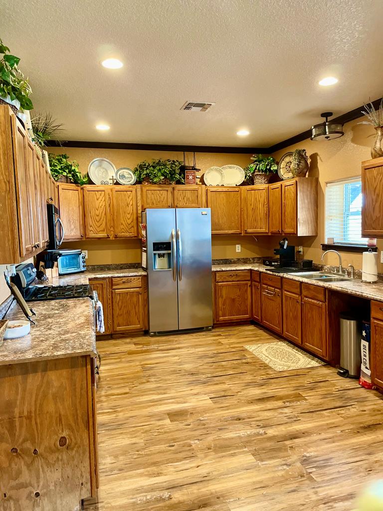 646 Victor Eckhardt Road Fredericksburg, TX 78624 - Photo 16 of 40 a kitchen with kitchen island granite countertop a stove a sink and a refrigerator