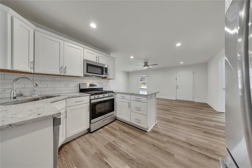 3940 Forrest Court Chamblee, GA 30341 - Photo 12 of 35 a kitchen with granite countertop a stove top oven a sink dishwasher and a refrigerator with wooden floor