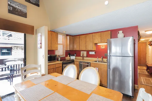 a kitchen with stainless steel appliances a refrigerator a stove a dining table and chairs