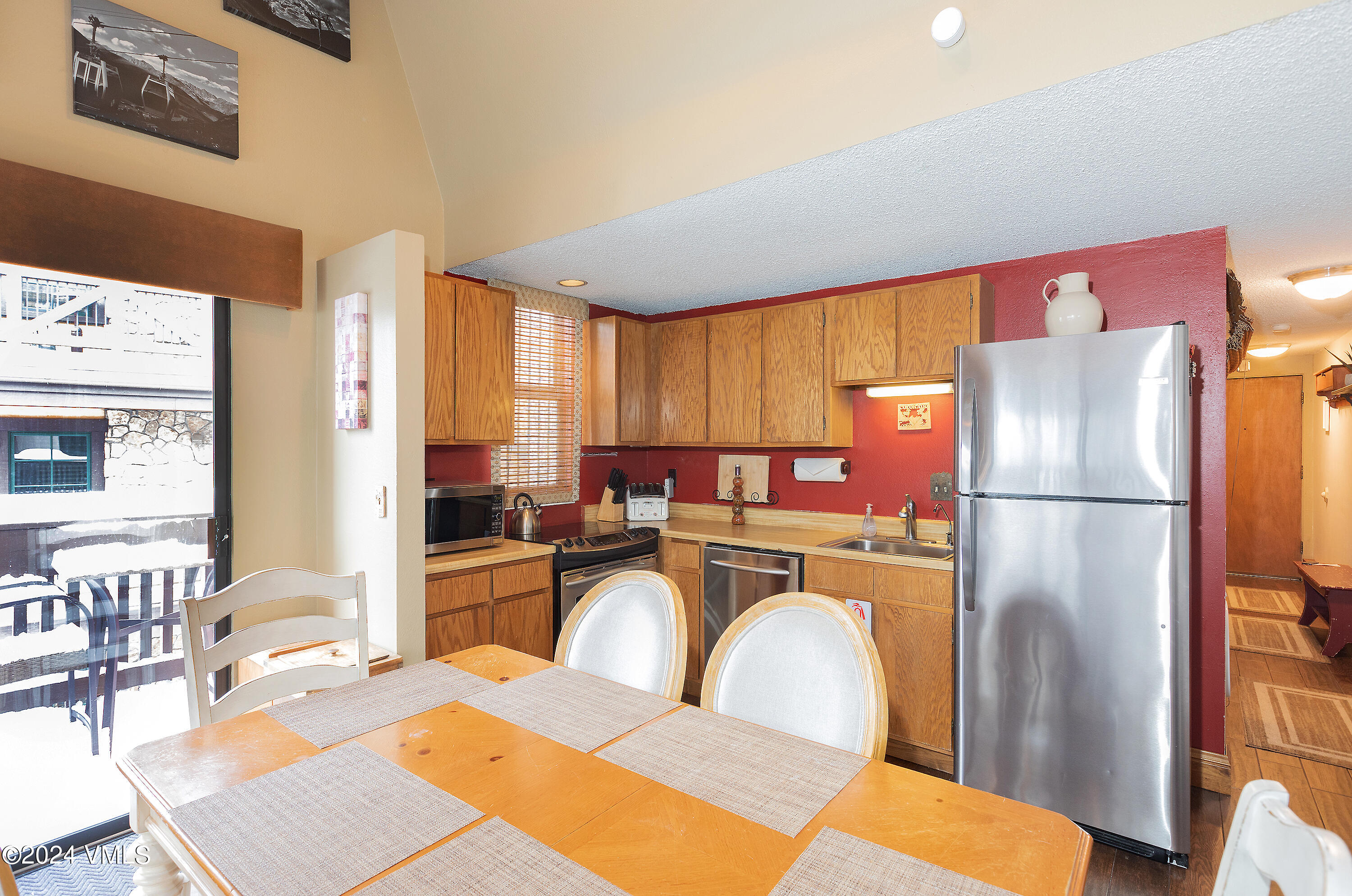 442 South Frontage Road East, Unit 306B Vail, CO 81657 - Photo 5 of 11 a kitchen with stainless steel appliances a refrigerator a stove a dining table and chairs