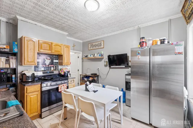 a kitchen with stainless steel appliances a stove a refrigerator a sink a dining table and chairs with wooden floor