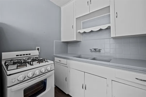 a kitchen with white cabinets stainless steel appliances and wooden floor