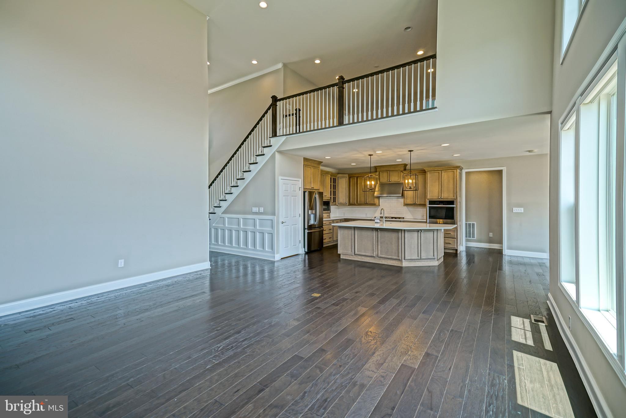 33557 Downing Circle Lewes, DE 19958 - Photo 14 of 89 a view of a hallway to an empty room with wooden floor and a kitchen