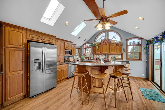 a kitchen with stainless steel appliances granite countertop a refrigerator a sink dishwasher a stove and white countertops with wooden floor