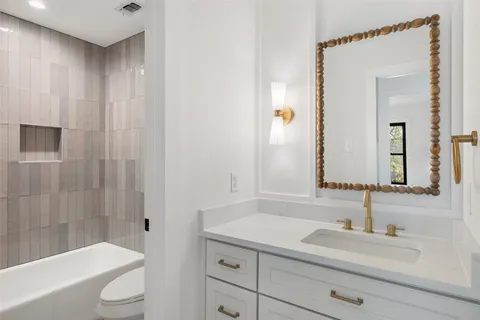 a bathroom with a sink a toilet a mirror and shower