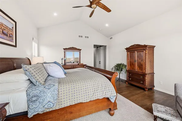 a bedroom with a bed and dresser with wooden floor
