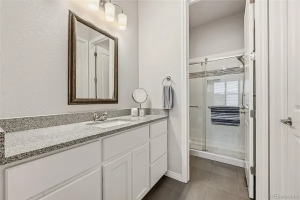 a bathroom with a granite countertop sink and a mirror