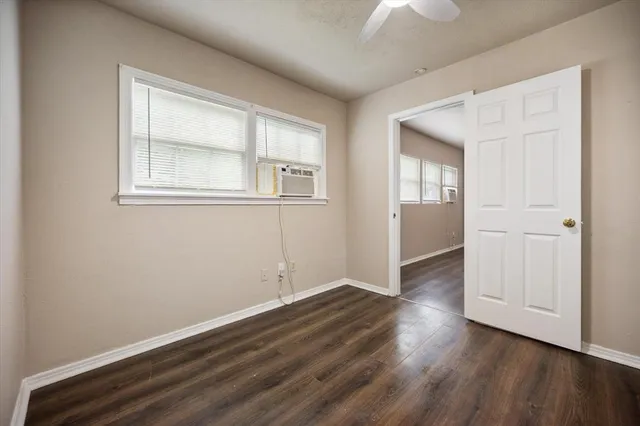 an empty room with wooden floor cabinet and windows