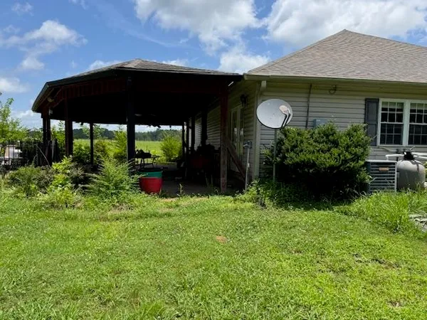 a backyard of a house with table and chairs under an umbrella