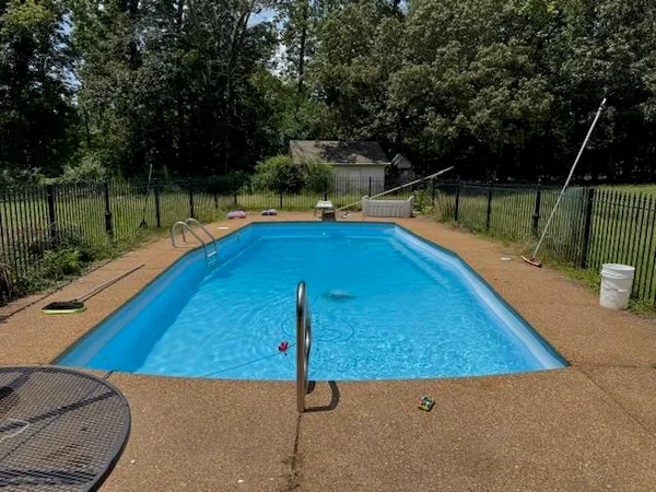 a view of a swimming pool with a patio and a yard
