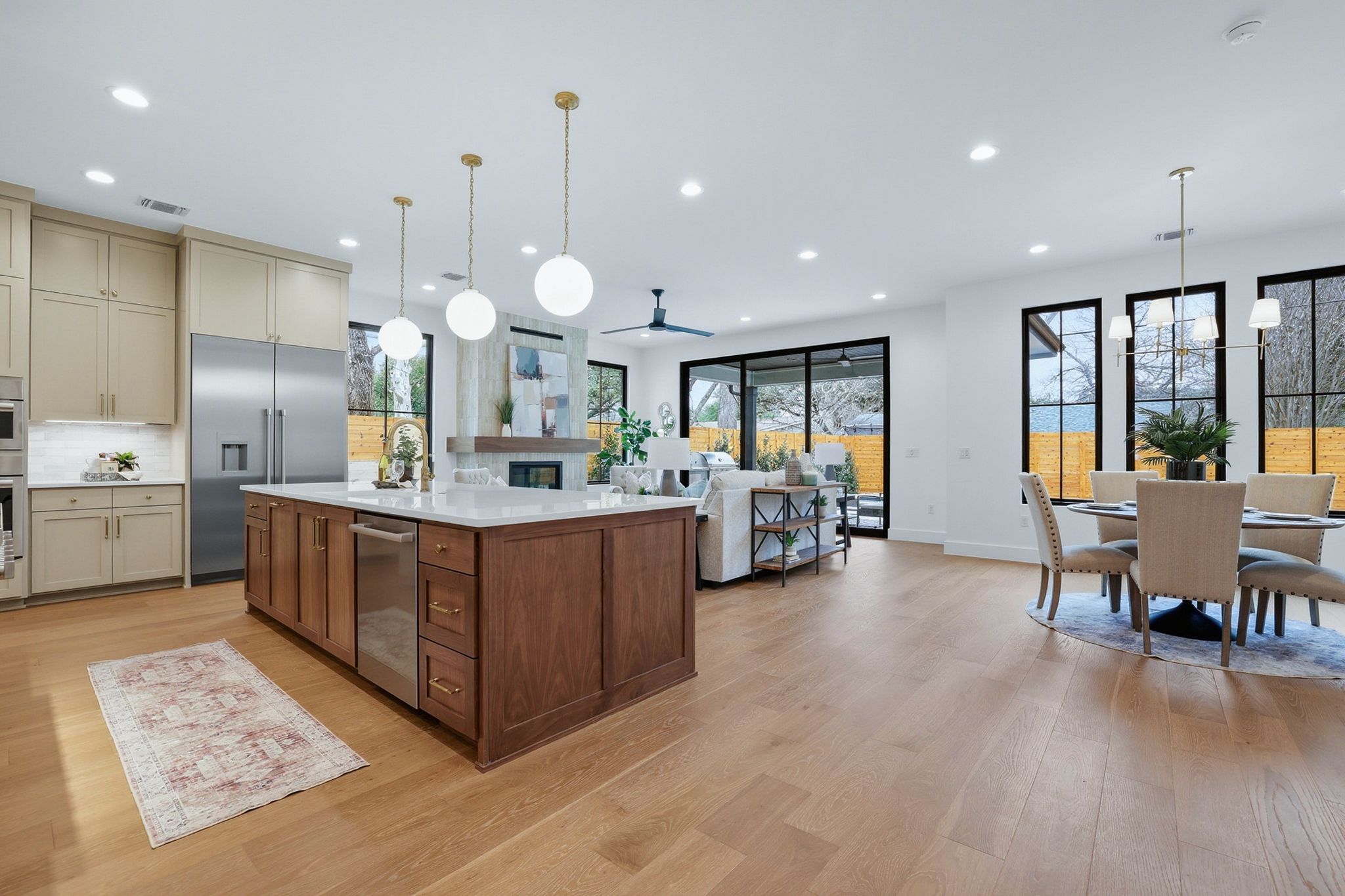 6611 Lexington Road Austin, TX 78757 - Photo 8 of 37 Open-concept living space featuring wood-finish flooring, a kitchen island with stone countertop, stainless steel appliances, and large black-framed windows