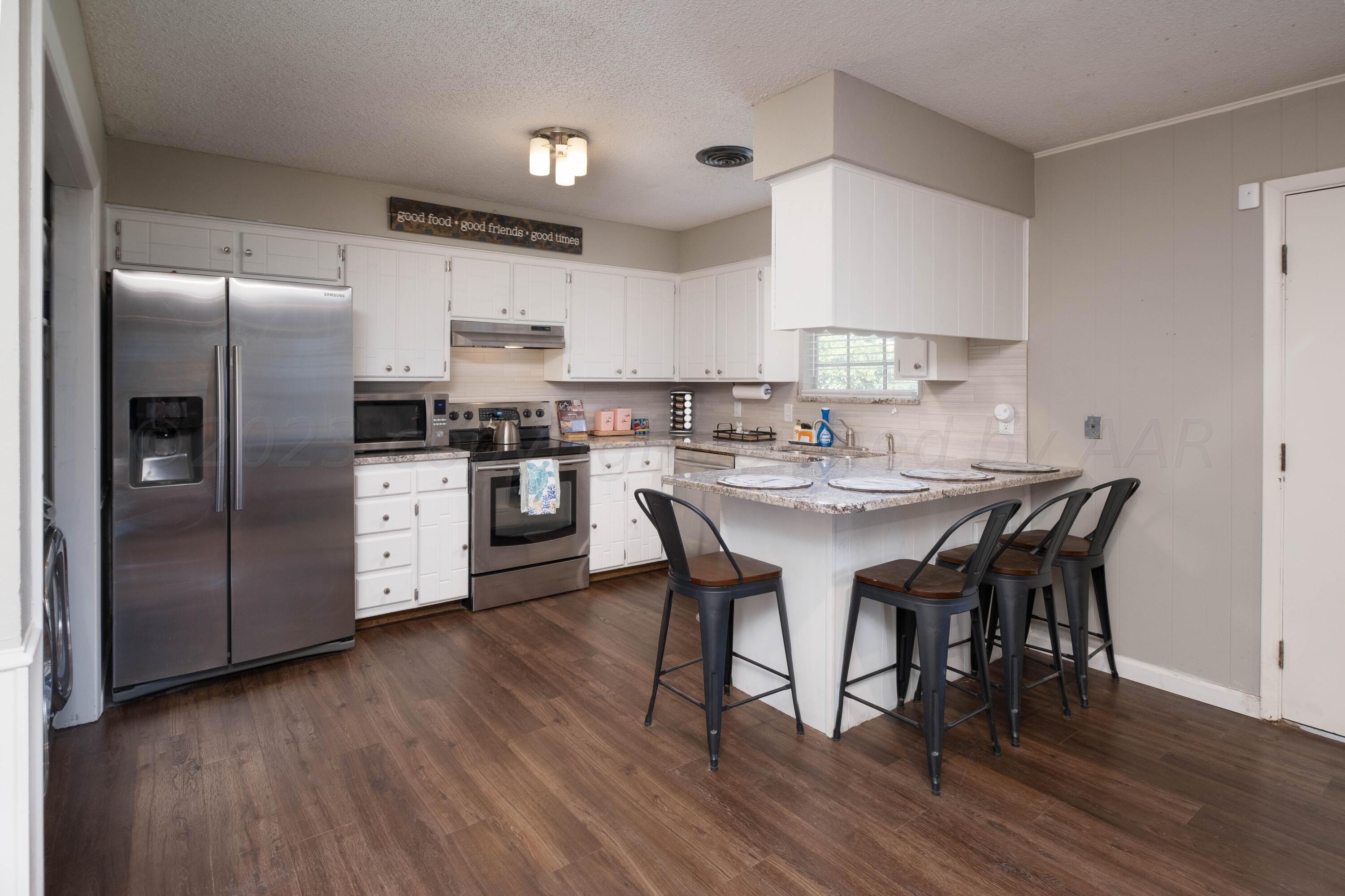 4813 South Rusk Street Amarillo, TX 79110 - Photo 11 of 23 a kitchen with stainless steel appliances a dining table chairs refrigerator and sink