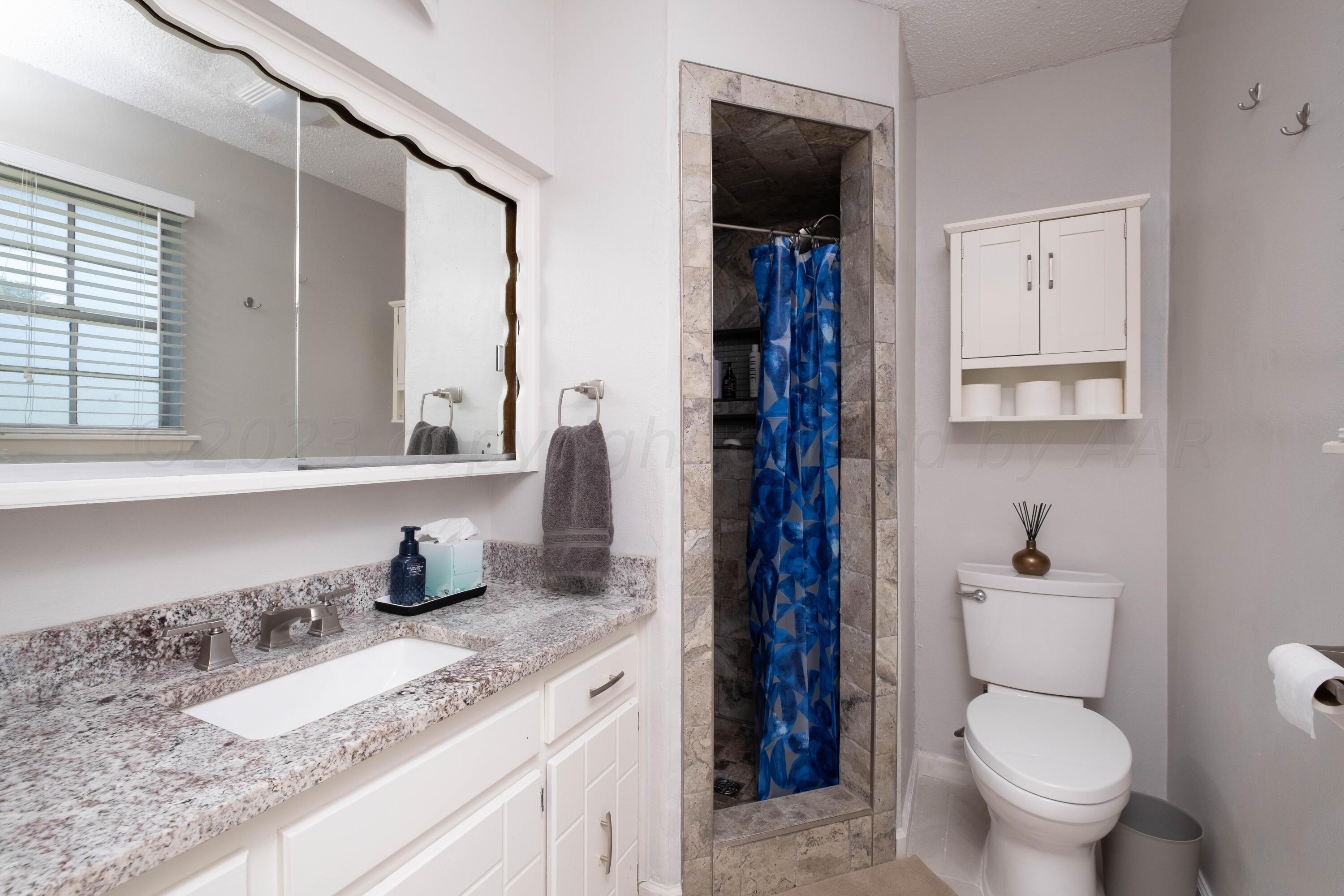 4813 South Rusk Street Amarillo, TX 79110 - Photo 17 of 23 a bathroom with a granite countertop toilet sink and mirror