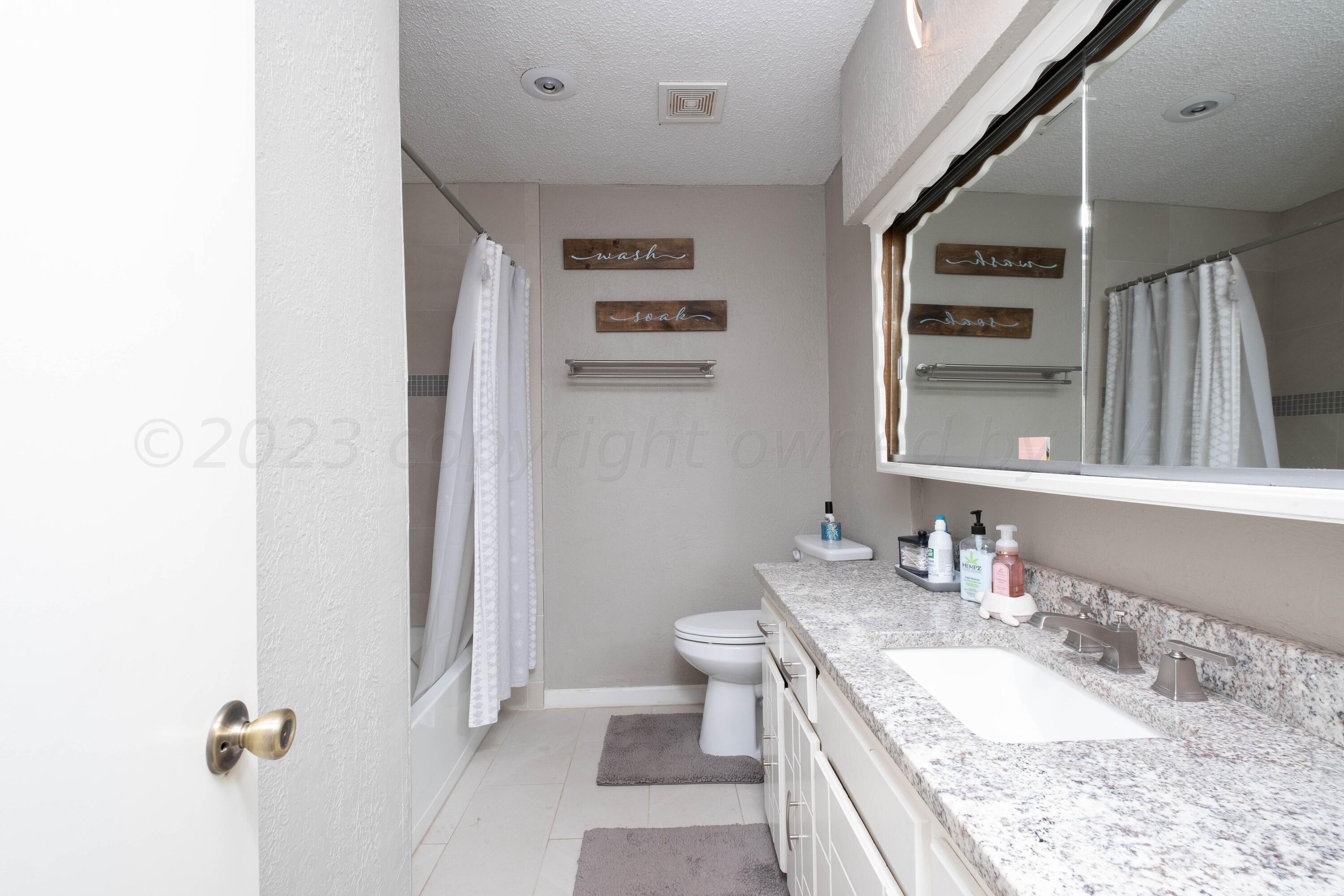 4813 South Rusk Street Amarillo, TX 79110 - Photo 19 of 23 a bathroom with a granite countertop sink mirror vanity and toilet