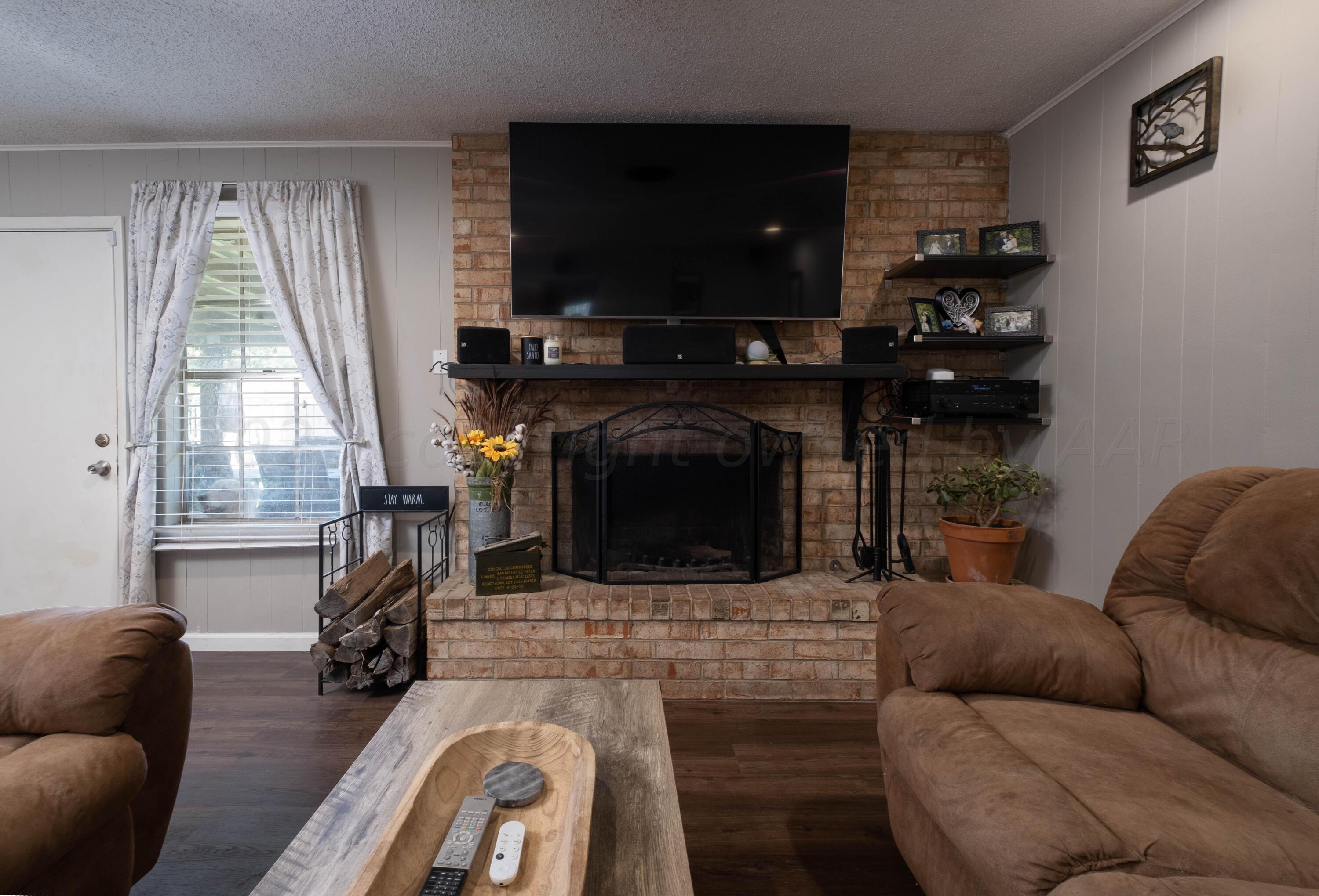 4813 South Rusk Street Amarillo, TX 79110 - Photo 10 of 23 a living room with furniture a flat screen tv and a fireplace