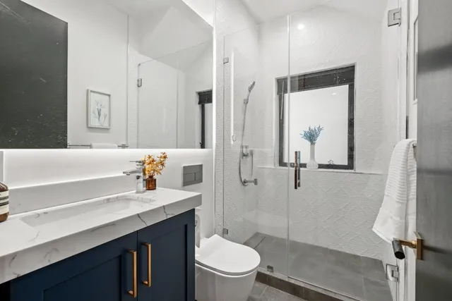 a bathroom with a granite countertop sink toilet and shower