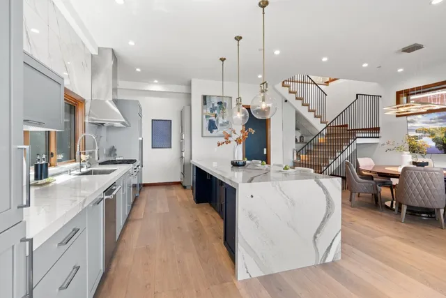 a kitchen with stainless steel appliances granite countertop a stove and a table chairs with wooden floor