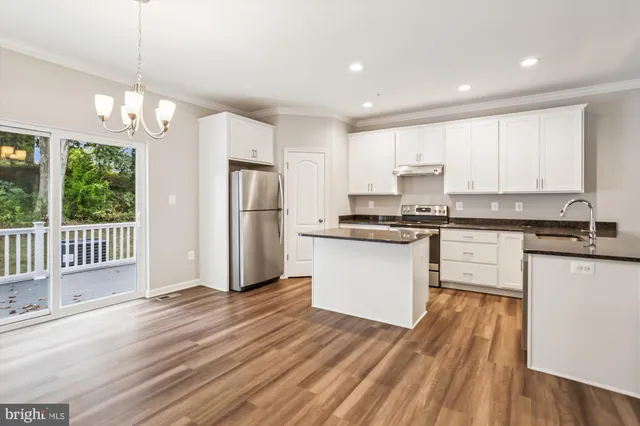 a kitchen with stainless steel appliances granite countertop a refrigerator a sink dishwasher a stove and white countertops with wooden floor