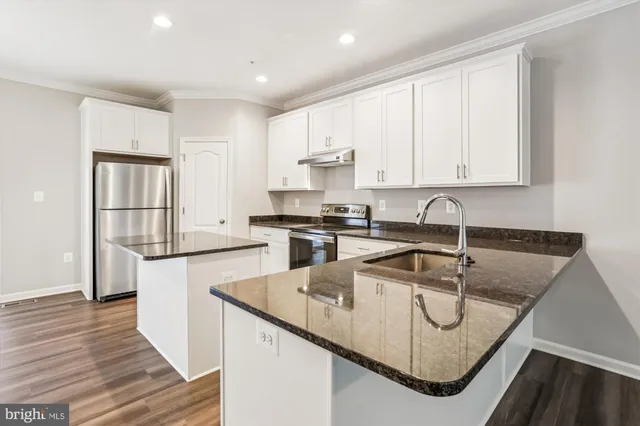 a kitchen with stainless steel appliances granite countertop a sink a stove and cabinets