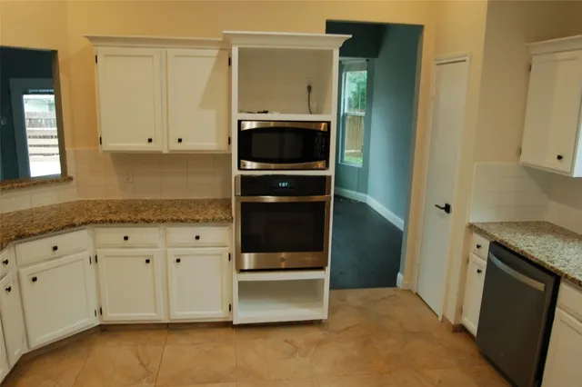 a kitchen with granite countertop white cabinets and refrigerator