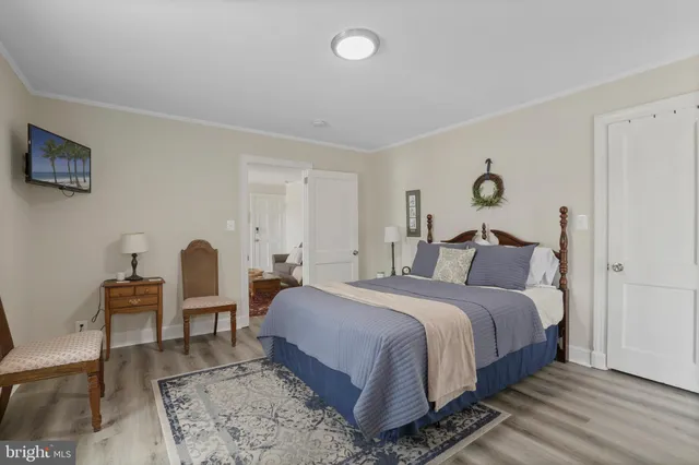 a bedroom with a bed a desk and chair with wooden floor