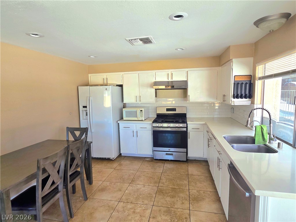 3648 Bronco Road Las Vegas, NV 89103 - Photo 3 of 24 A well-lit culinary space features bright cabinetry, subway tile backsplash, and durable tile flooring.