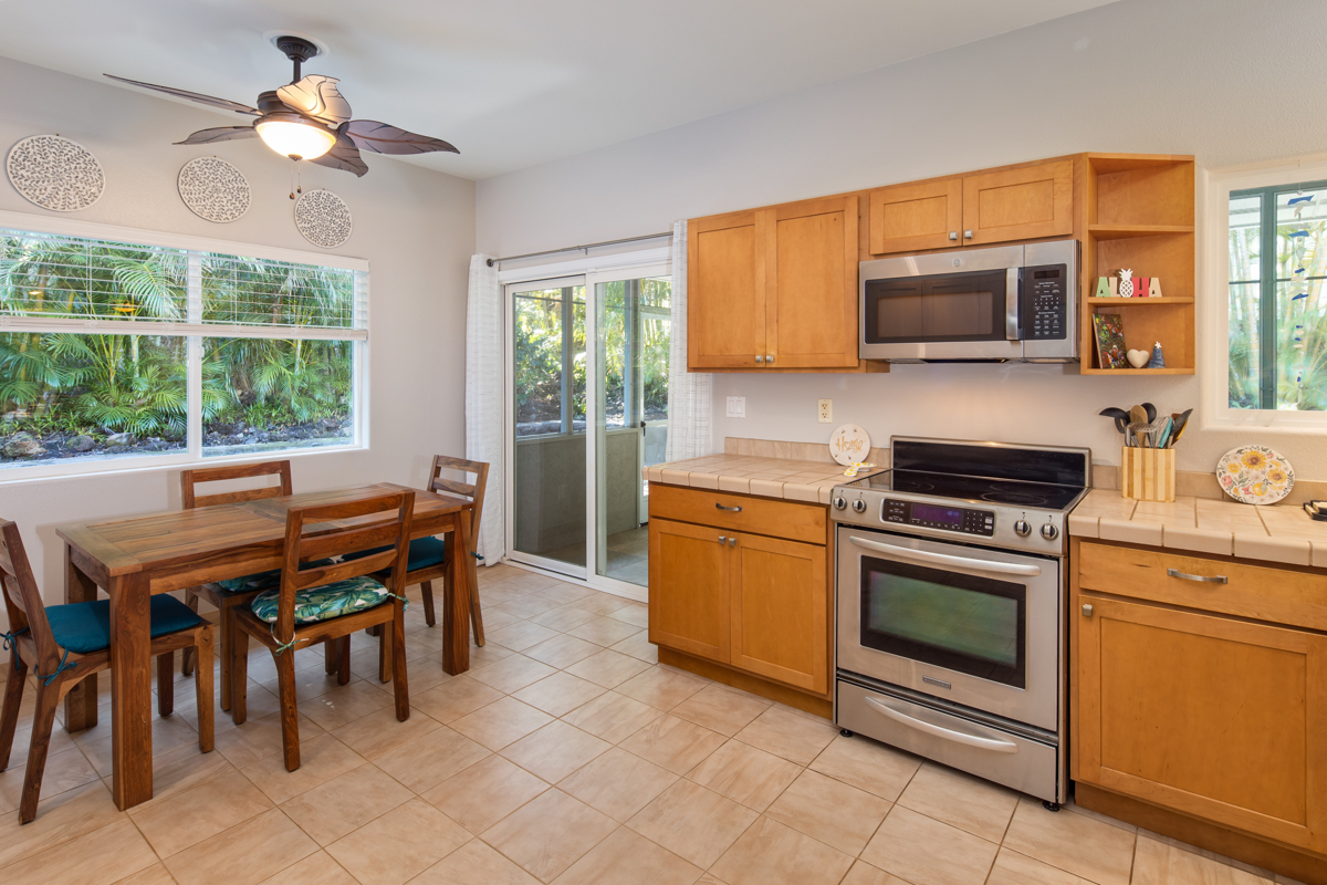 68-1736 Ka'apuni Street Waikoloa, HI 96738 - Photo 9 of 30 a kitchen with stainless steel appliances granite countertop a stove top oven a sink dishwasher a dining table and chairs with wooden floor